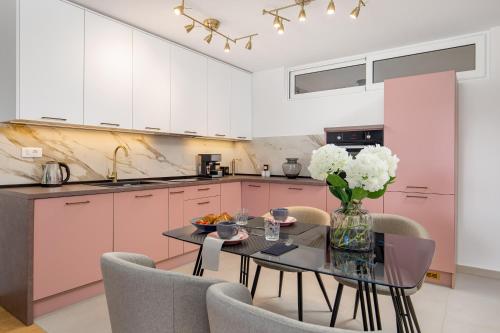 cocina con armarios rosas, mesa y sillas en Seaview apartment „Megan“ with sunny terrace en Kastav