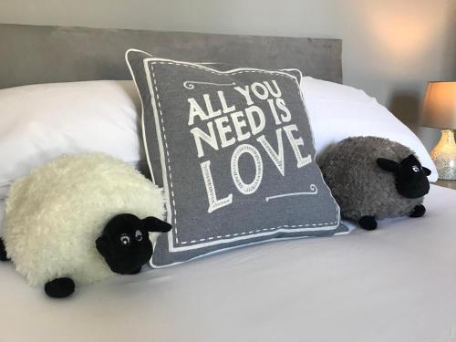 duas ovelhas empalhadas estão sentadas numa cama com uma almofada em Inn Cardiff em Cardiff