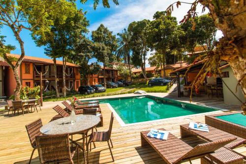 un patio con mesa y sillas junto a una piscina en Tororao Hotel Pousada, en Arraial d'Ajuda