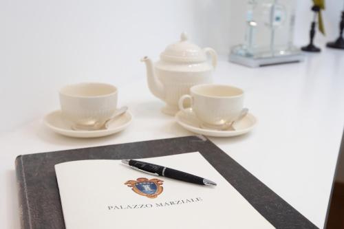 a pen sitting on a paper next to two cups at Palazzo Marziale in Sorrento