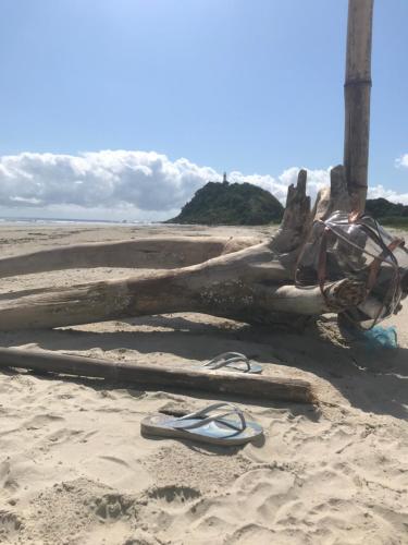 a pair of flip flops on a beach next to a tree branch at Pousada das Gêmeas in Ilha do Mel