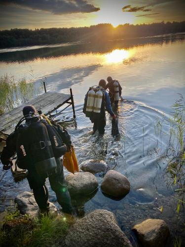 a group of people walking into a body of water at Mazurski Domek - Wake Up Home Ogonki in Ogonki