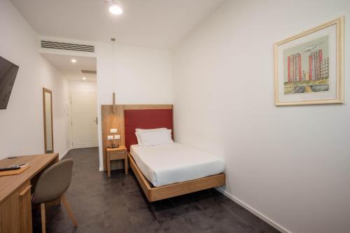 Habitación pequeña con cama, escritorio y escritorio. en V Hotel, en Ancona