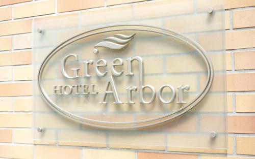 a sign for a green hotel addict on a brick wall at Hotel Green Arbor in Sendai