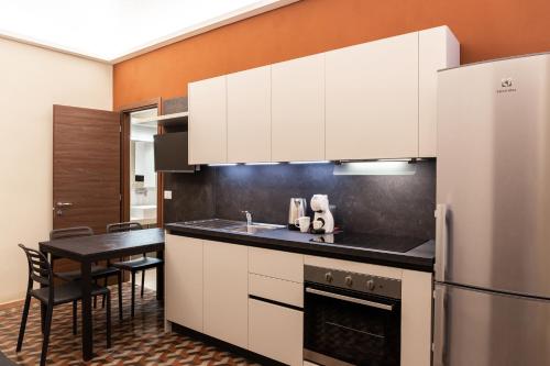 uma cozinha com armários brancos, uma mesa e um frigorífico em ROMA COMFORT em Casale Monferrato