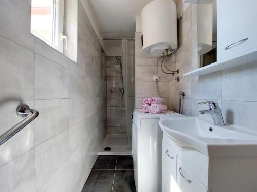 La salle de bains blanche est pourvue d'un lavabo et d'une douche. dans l'établissement Apartment Tamarut, à Crikvenica