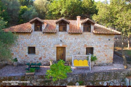a stone house with two chairs in front of it at Kefalonian Luxury Villas in Kástron