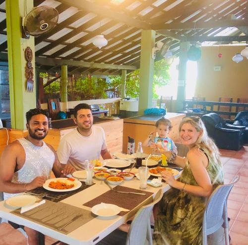 a group of people sitting at a table eating food at Villa 252 Kosgoda in Kosgoda