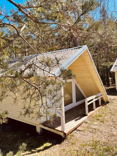 a tiny house with a porch in a yard at Energetikas • nameliai prie jūros in Šventoji
