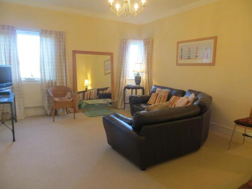 a living room with a leather couch and a television at Sandy Shores in Hunstanton