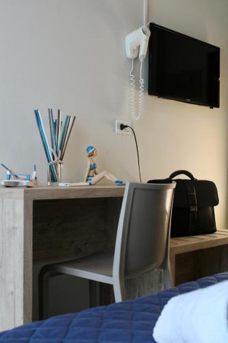 a bedroom with a desk with a chair and a television at Hotel Adigrat in Riccione
