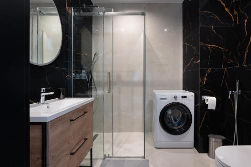 a bathroom with a shower and a washing machine at Apartament 1612 Modern Tower Gdynia in Gdynia