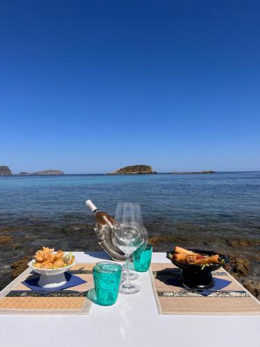 una mesa con un plato de comida y una copa de vino en Jacaranda Apartments & Studios, en Es Canar