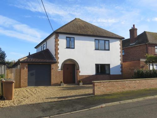 a white house with a brown door on a street at Seaside Retreat in Hunstanton