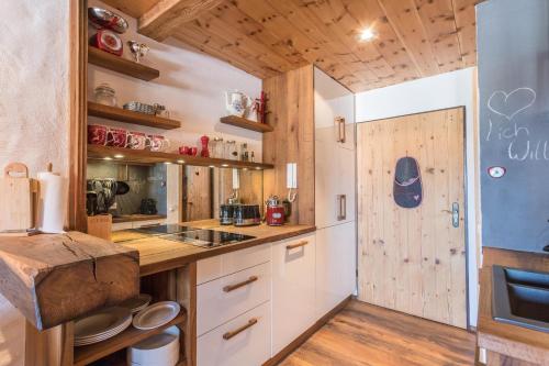 a kitchen with white cabinets and a wooden wall at Alpenauszeit im Zirbenholz Chalet in Inzell