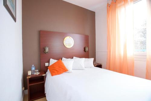 een slaapkamer met een groot wit bed en een oranje kussen bij Hôtel Les Gens De Mer Lorient by Popinns in Lorient