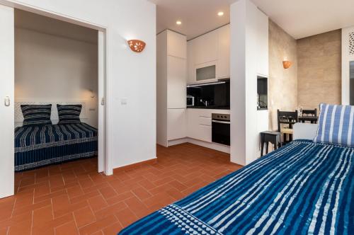 a bedroom with two beds and a kitchen with a table at Akisol Santa Luzia Teltale in Santa Luzia