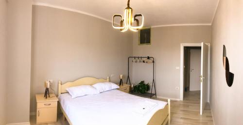 una camera con letto bianco e lampadario pendente di Diti's Apartment a Shkodër