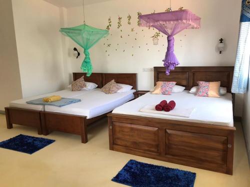 ネゴンボにあるAnna Tourist Innのベッド2台 壁にパラソルが付いた部屋