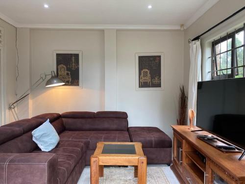 a living room with a brown couch and a table at Le Residence de Josephine in Kloof