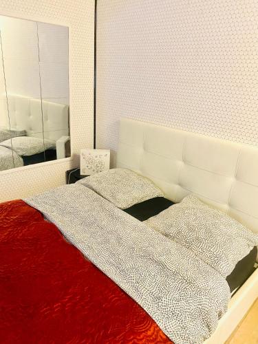 - un lit avec une couverture rouge et un miroir dans l'établissement Au pied de la tour Eiffel Trocadéro, à Paris