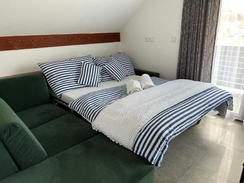 een bed met gestreepte kussens op een groene bank bij Apartmán D5 Nová Pec in Nová Pec