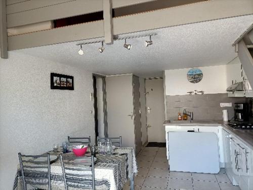 uma cozinha com mesa e cadeiras num quarto em Maison avec piscine collective sur Gruissan 6MIN39 em Gruissan