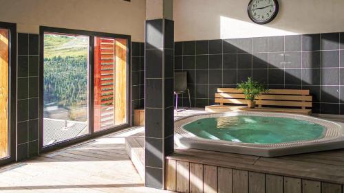 a bathroom with a hot tub with a clock on the wall at Résidence Dormio Resort Les Portes du Grand Massif - Flaine in Flaine