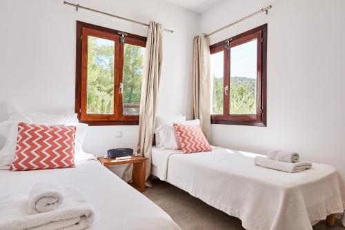 two beds in a room with two windows at Casa Kiva in Es Cubells