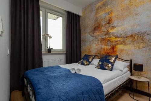 a bedroom with a bed with blue sheets and a wall at Home Factory Estate Praga Kotsisa by Renters in Warsaw