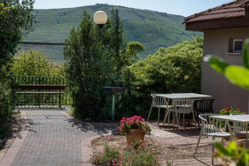 a patio with a table and chairs and a bench at Kibbutz Malkiya Travel Hotel in Malkiyya