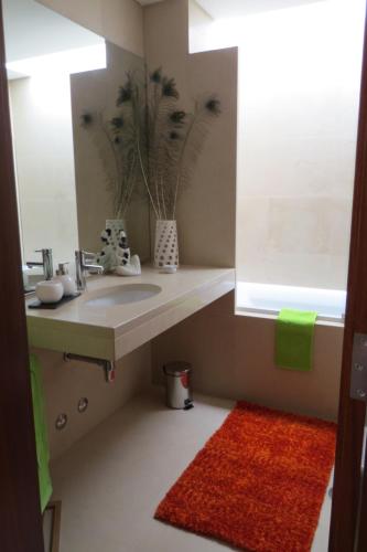 a bathroom with a sink and a mirror and a red rug at Estúdio de luxo em condomínio privado com piscina in Cais Novo