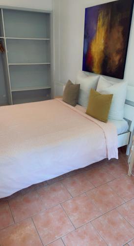 a bedroom with a white bed with a painting on the wall at Chambre cosy in Arles