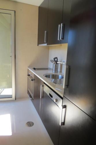 a kitchen with a sink and a stainless steel refrigerator at Estúdio de luxo em condomínio privado com piscina in Cais Novo