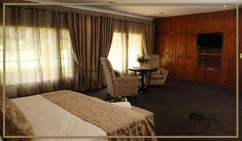 a hotel room with a bed and a table and chairs at Water on Waldrift Guesthouse in Vereeniging