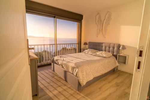 une chambre avec un lit et un balcon avec vue dans l'établissement Les Marines du Soleil - Vue Mer, à Patrimonio