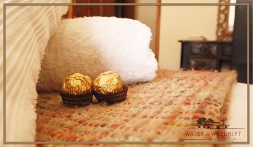 two muffins sitting on a bed with white sheets at Water on Waldrift Guesthouse in Vereeniging