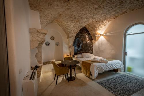 um quarto com uma cama e uma mesa num quarto em Ceglie Suites & Apartments - Celso em Ceglie Messapica