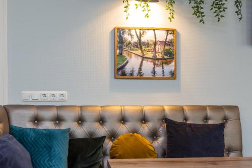 a couch in a living room with a picture on the wall at Hotel Giethoorn in Giethoorn