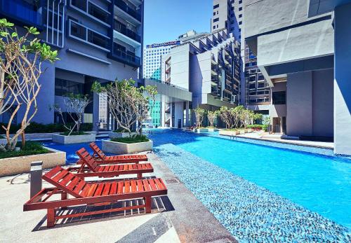 a swimming pool with red lounge chairs in a building at Imperio Residences Melaka Malacca in Melaka