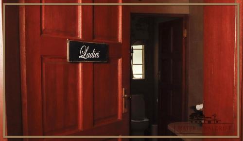 a door to a bathroom with a sign on it at Water on Waldrift Guesthouse in Vereeniging