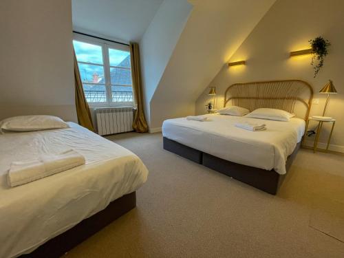 a bedroom with two beds and a window at Maison des fleurs in Saint-Aignan