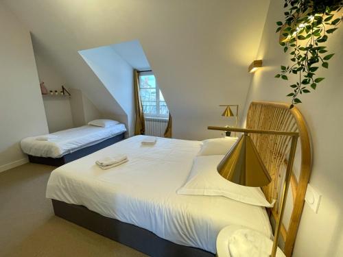 um quarto com 2 camas e lençóis brancos em Maison des fleurs em Saint-Aignan