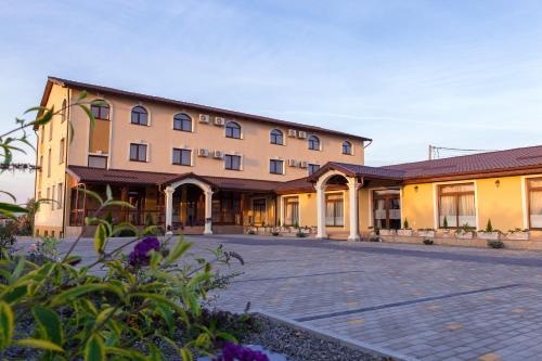 a large building with a courtyard with purple flowers at Pensiunea Select in Alba Iulia