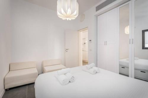 a white bedroom with a large bed and a couch at Modern and Design 1 BD apt close to the beach in Tel Aviv