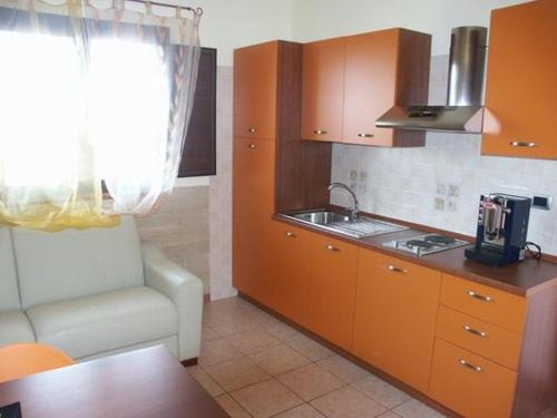 eine Küche mit orangefarbenen Schränken, einem Stuhl und einem Waschbecken in der Unterkunft Oasi degli Angeli in Zapponeta
