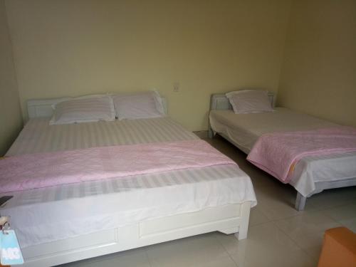 two beds in a bedroom with pink and white sheets at Hoa Lan Hotel in Bak Kan