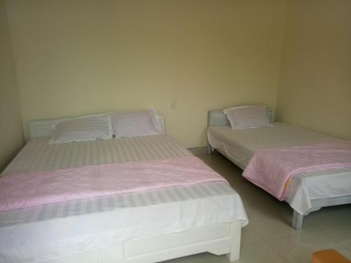 two beds in a bedroom with pink and white sheets at Hoa Lan Hotel in Bak Kan