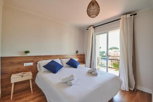 um quarto com uma grande cama branca com almofadas azuis em Costa Brava E-4 em Calella de Palafrugell