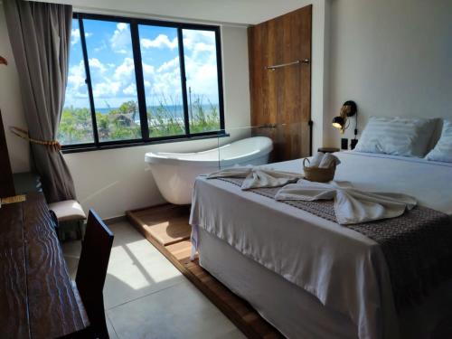 ein Schlafzimmer mit einer Badewanne, einem Bett, einer Badewanne und einem Fenster in der Unterkunft Malai Boutique Hotel in Fortaleza